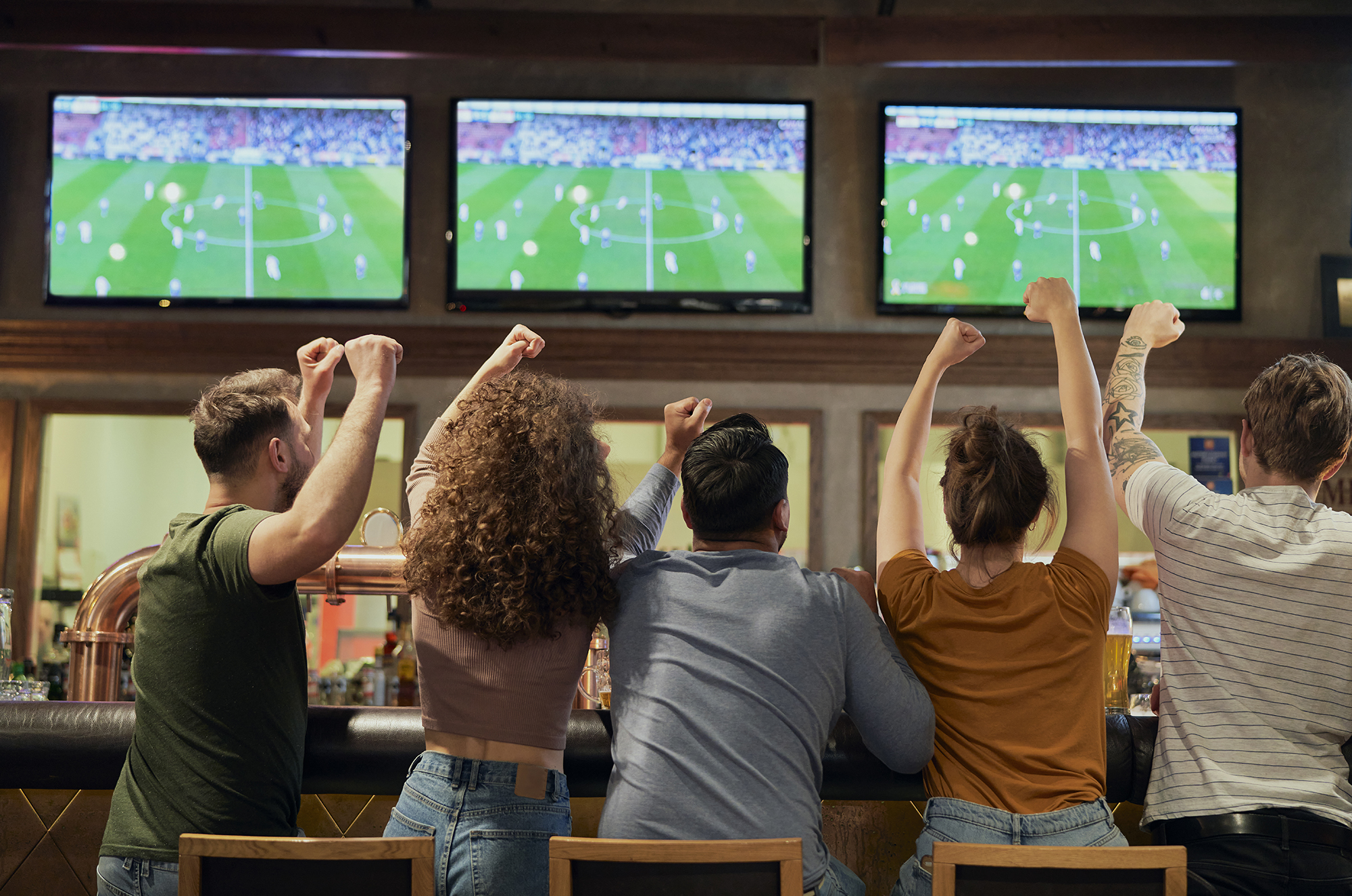 Fans cheering while watching soccer in a pub